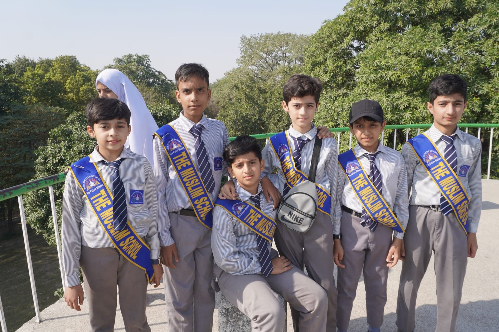 A group of students in school uniform beside a garden fence.