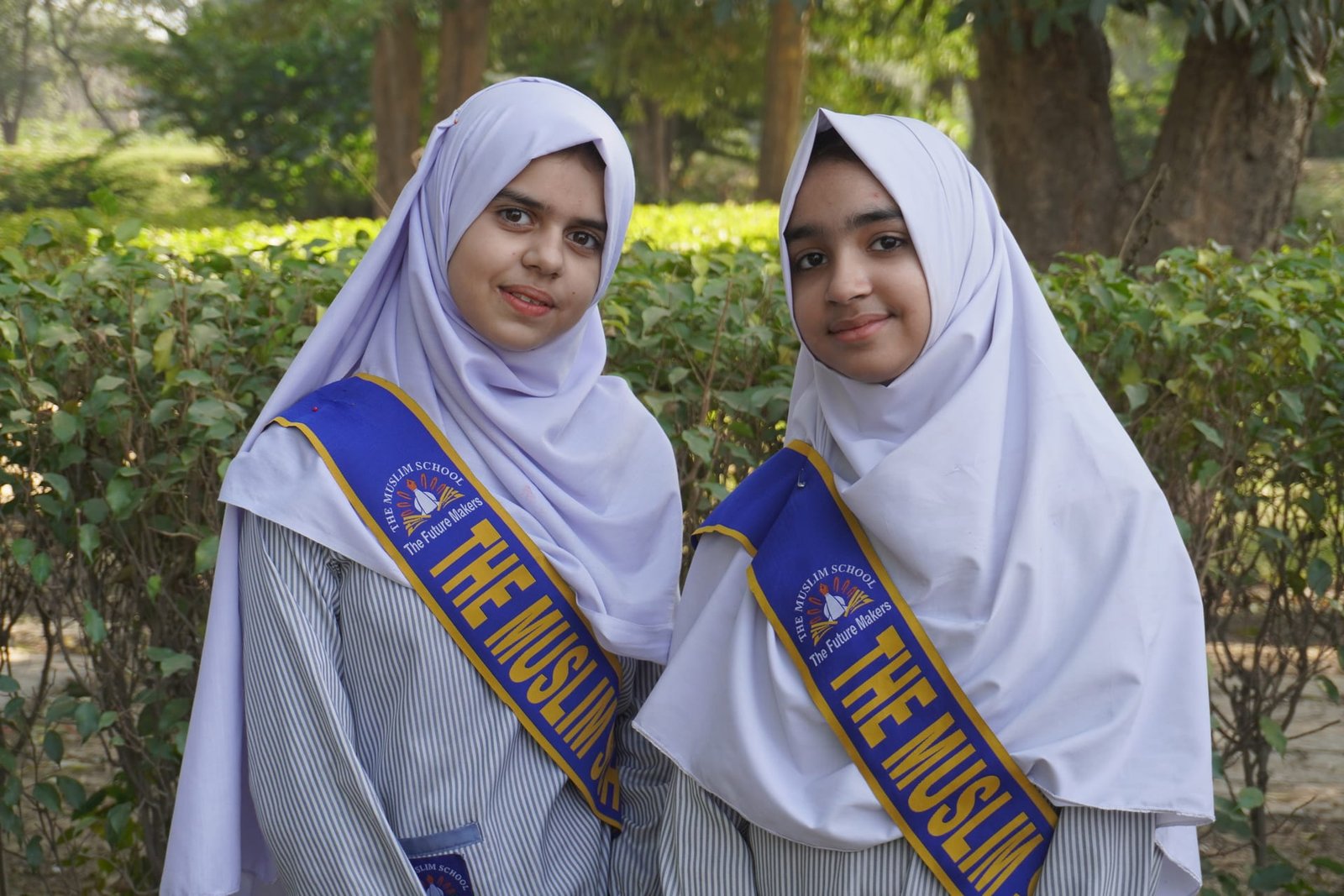 Two students in school uniform during an outdoor group visit.